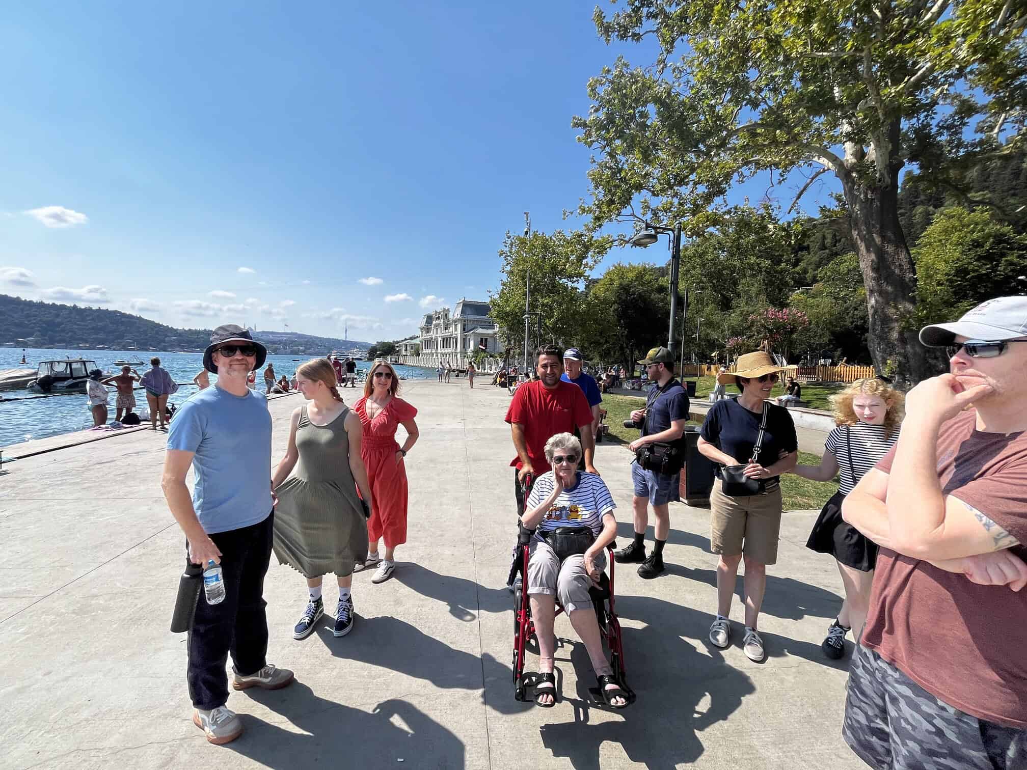 A group walking the Bebek waterfront, one guest using a wheelchair