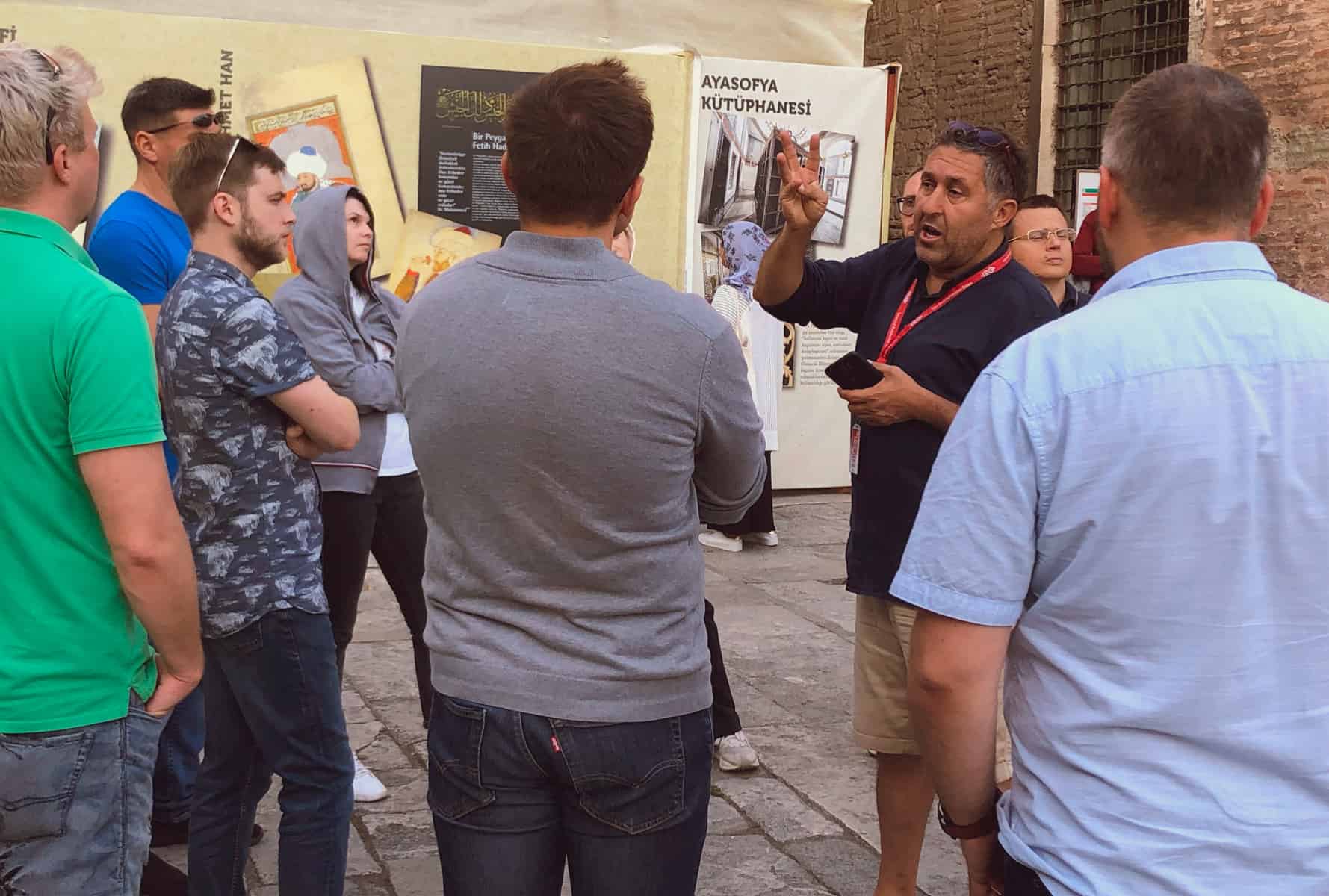 A licensed guide talking a corporate group through a wall of exhibits