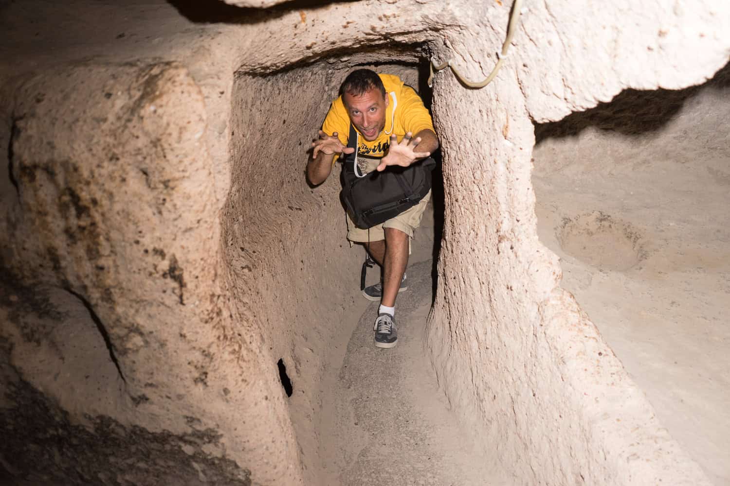 A visitor stooping through a rock-cut tunnel in Kaymaklı Underground City