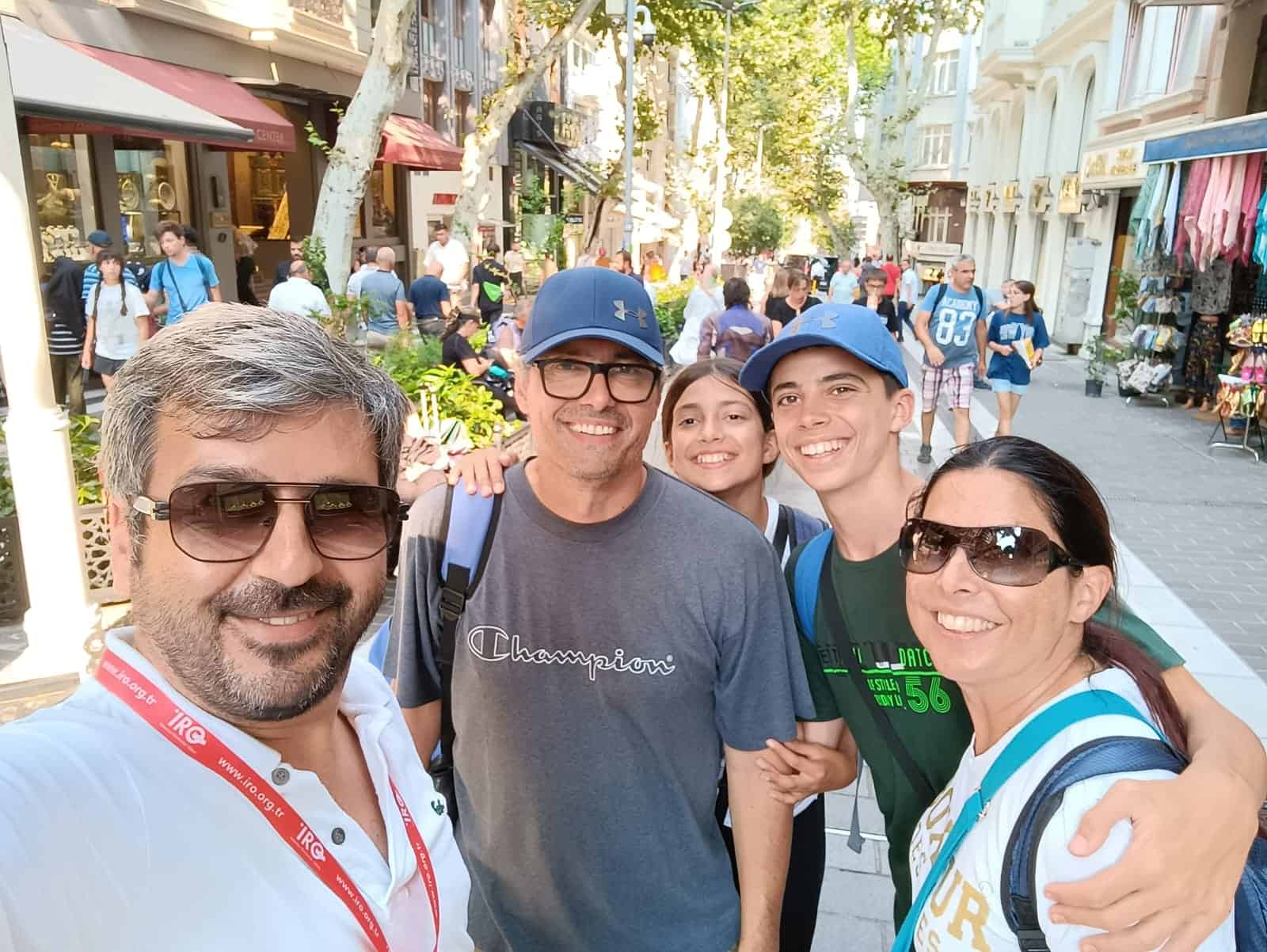 Rubil Gündüz, wearing his guide card, in a selfie with a family of guests on an Istanbul street