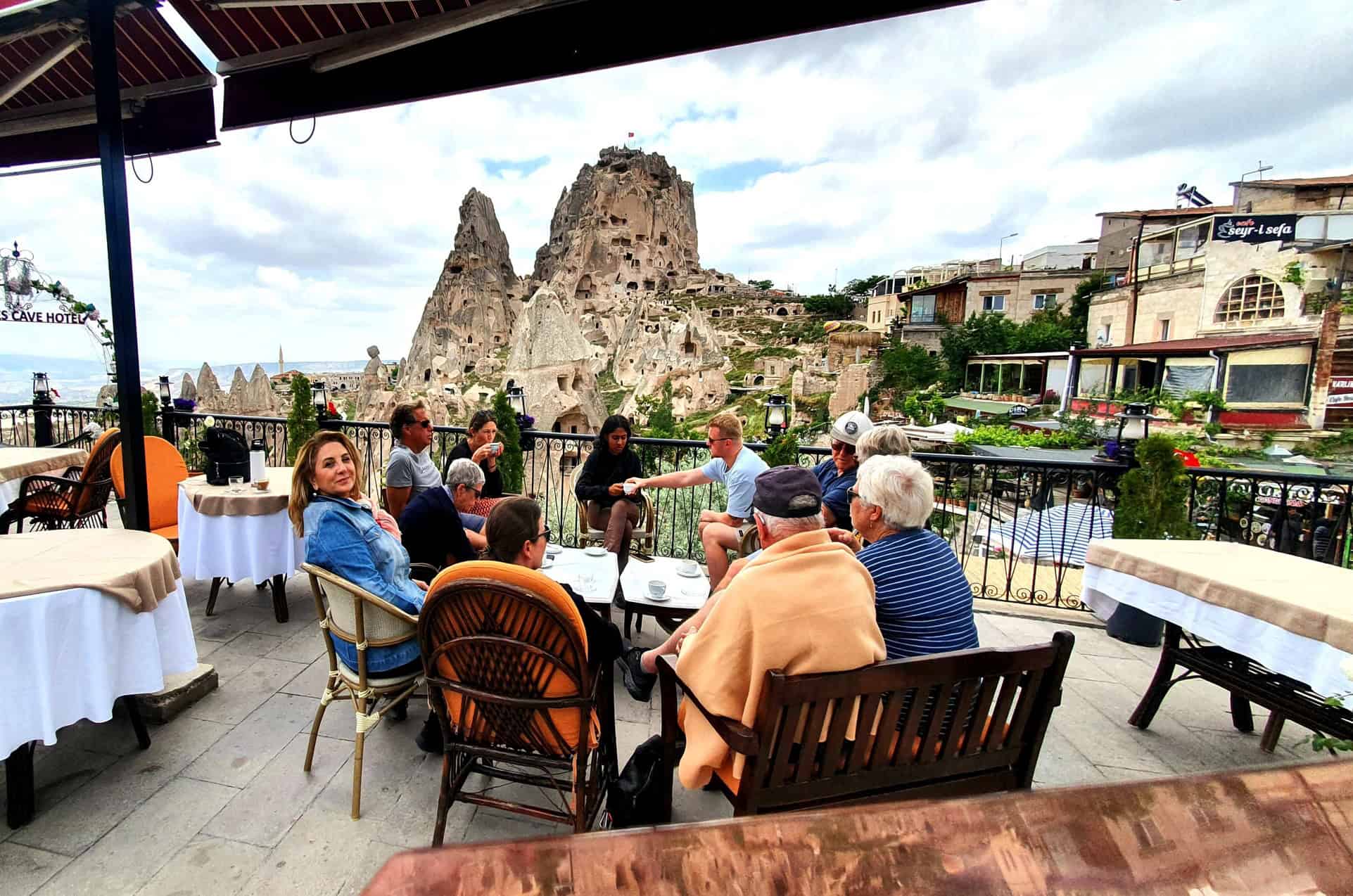 Guests at a terrace table facing the rock castle of Uçhisar