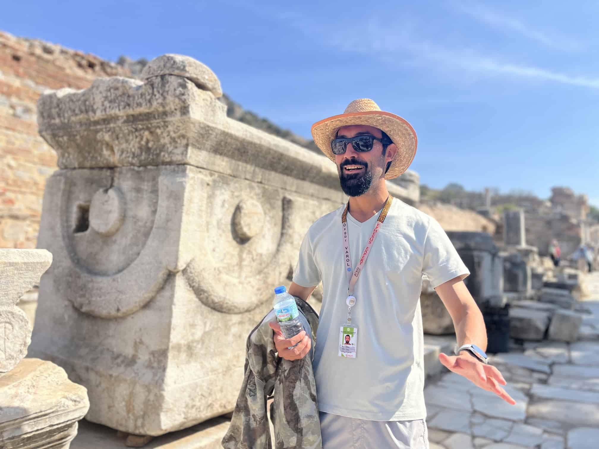 Ozgur Varol in a sun hat beside a carved marble block at Ephesus