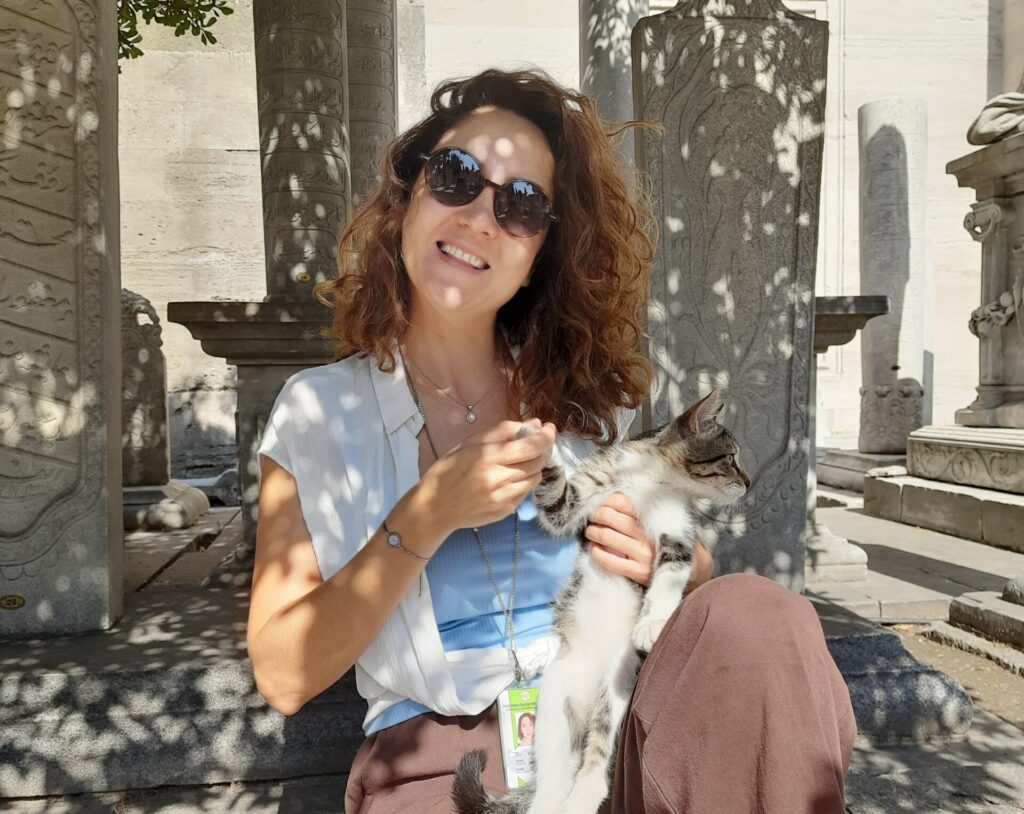 Betül Başak with a cat among marble columns at an Aegean site