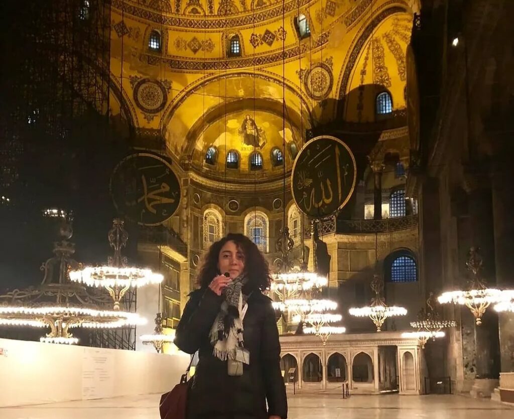 Tour guide Betül Başak inside Hagia Sophia, the gilded Byzantine interior visible behind her