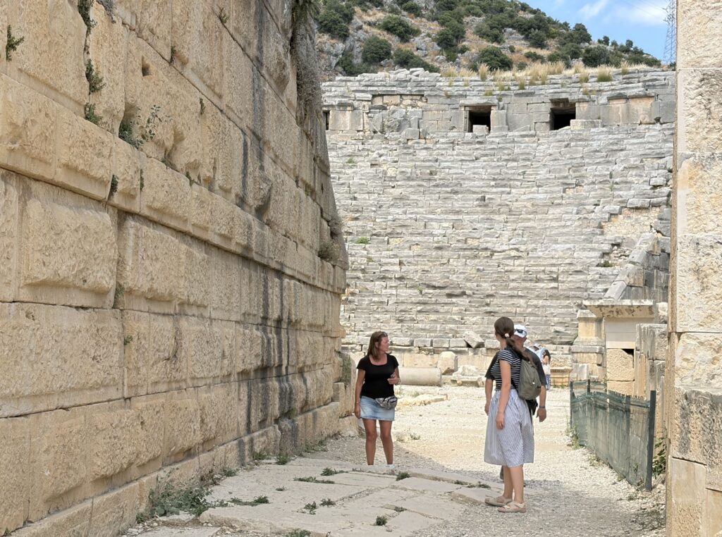 Guide standing with two guests at the base of the Lycian cliff tombs at Myra ancient city, Demre