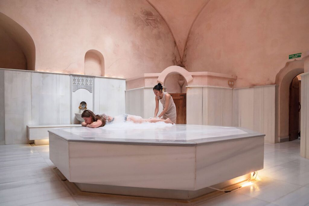 Guest receiving soap foam massage on octagonal göbek taşı under vaulted ceiling at Karaköy hamam
