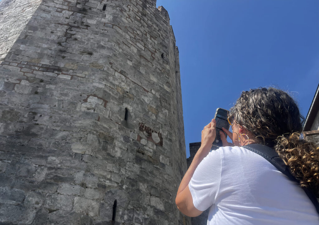 Visitor photographing the exterior of an Ottoman tower at Yedikule Fortress Istanbul from directly below, blue sky behind
