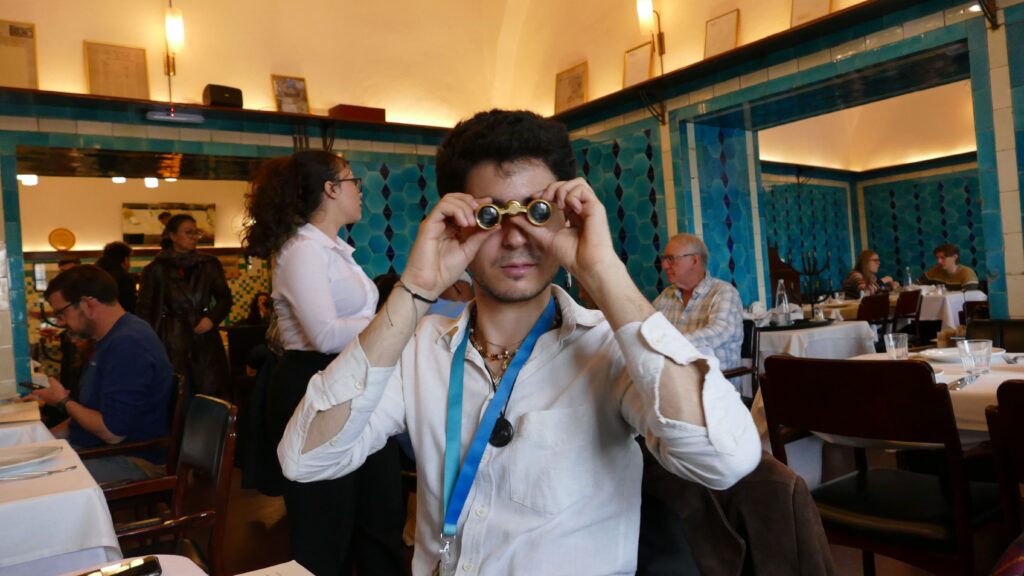 Tour guide holding opera glasses inside Pandeli restaurant Istanbul, turquoise İznik tile walls behind