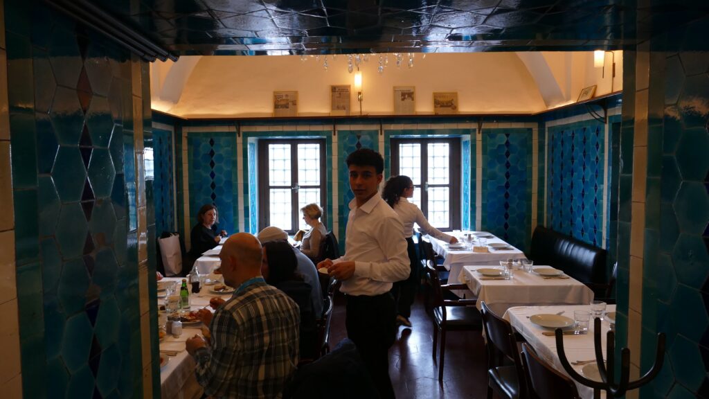 Interior dining room at Pandeli restaurant Istanbul, waiter serving lunch beneath arched tiled walls