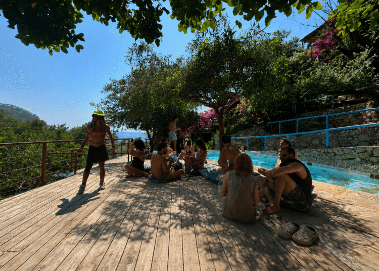 Travelers relaxing by a swimming pool surrounded by nature in Kabak Valley near Fethiye, Türkiye.