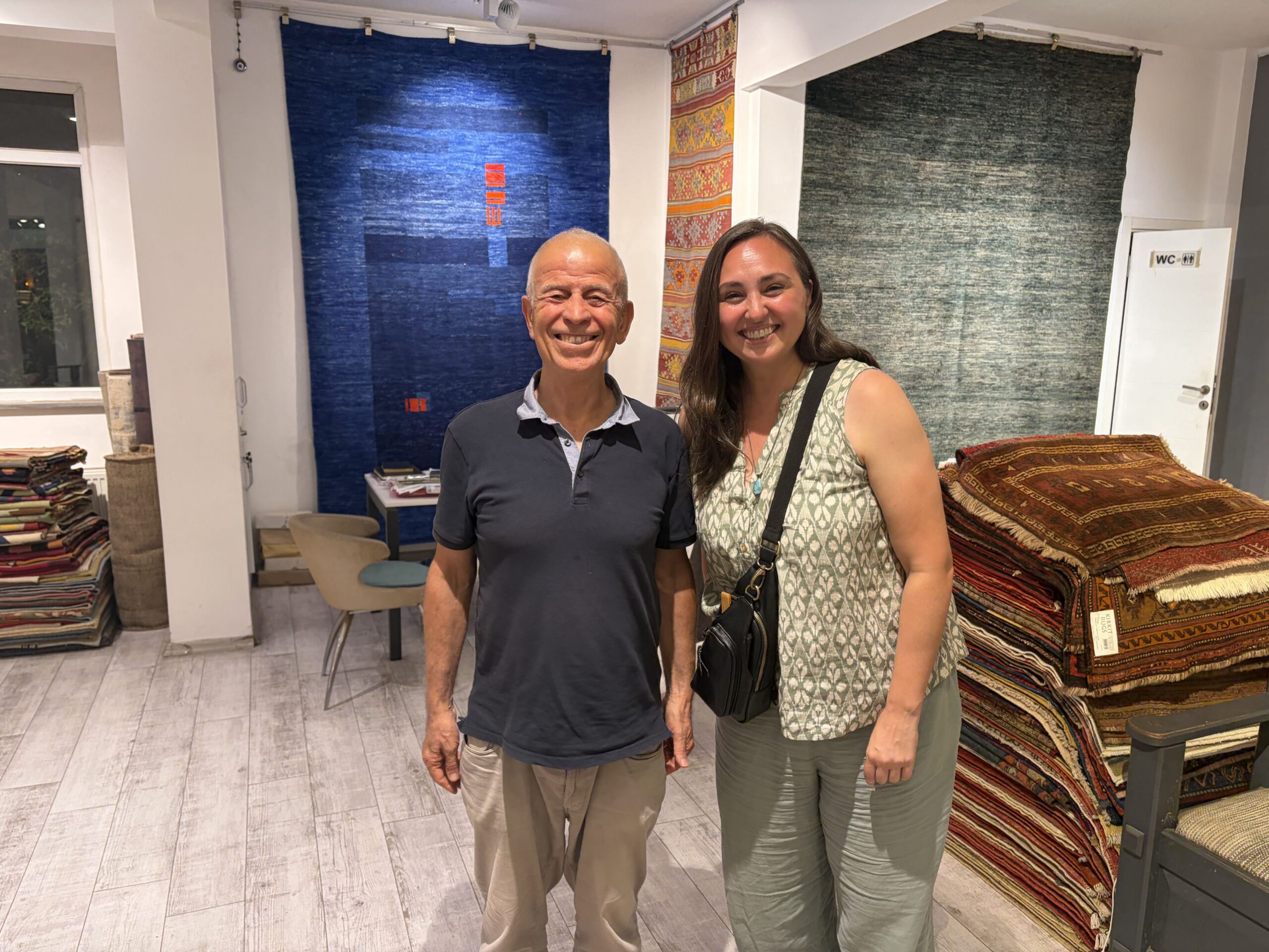 Ahmet Diler posing with a visitor inside the Kirkit Rugs gallery in Sultanahmet, Istanbul, surrounded by traditional Turkish kilims.