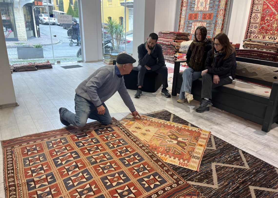 Ahmet Diler introducing visitors to the symbolism, history, and weaving techniques of a traditional Turkish kilim at Kirkit Rugs in Istanbul.
