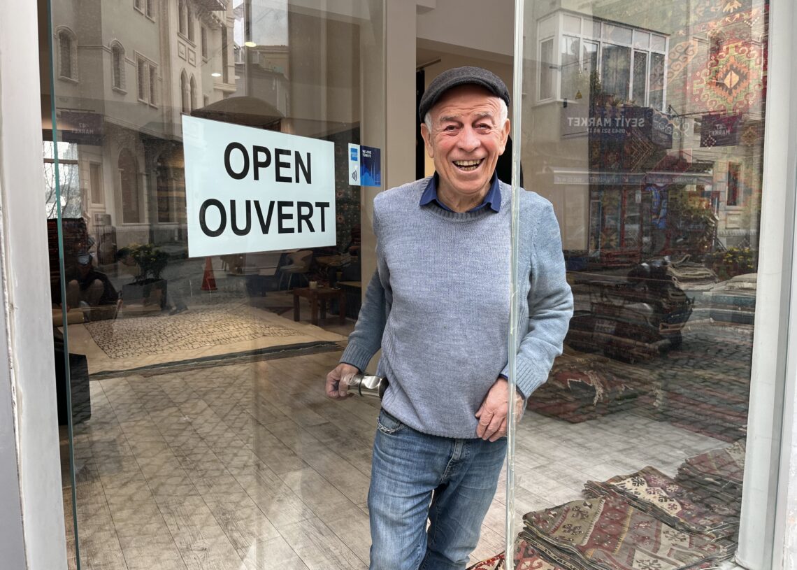 Ahmet Diler standing at the entrance of Kirkit Rugs in Sultanahmet, Istanbul, welcoming visitors to his traditional Turkish rug gallery.