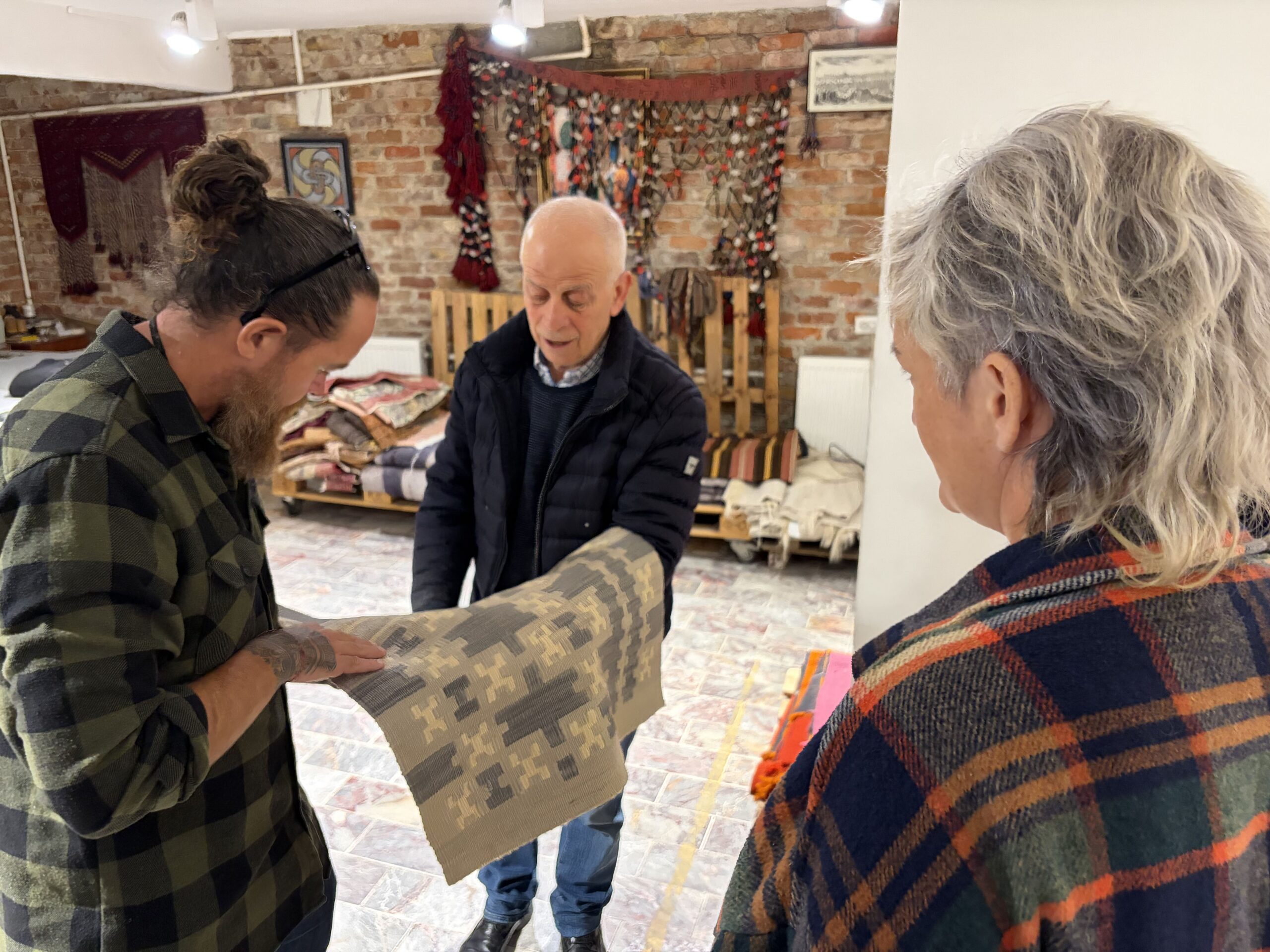 Ahmet Diler presenting a handwoven Turkish kilim and explaining its motifs, weaving techniques, and craftsmanship to visitors at Kirkit Rugs in Istanbul.