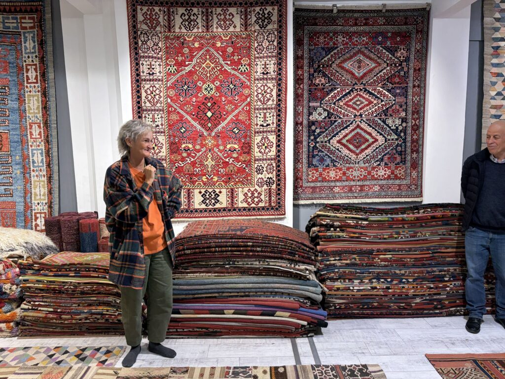 Visitor exploring a collection of traditional Turkish kilims and rugs displayed inside the Kirkit Rugs gallery in Sultanahmet, Istanbul.