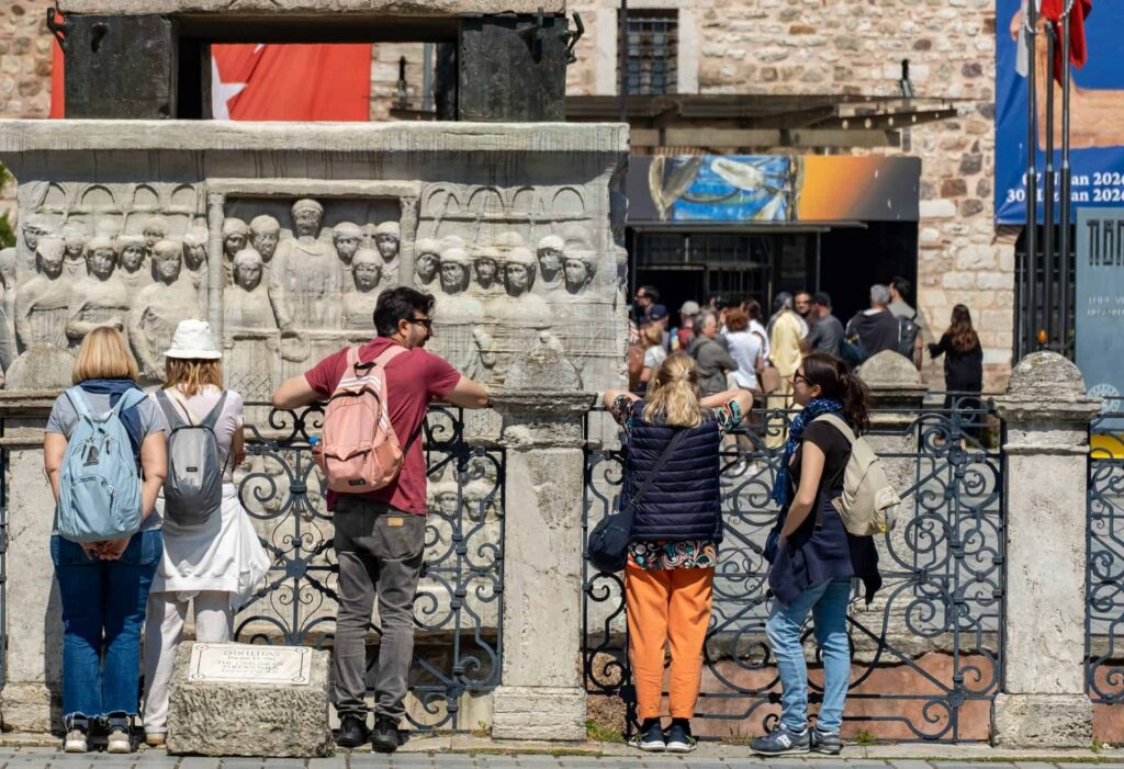 Tour guide explaining the Column of Constantine to visitors in Sultanahmet, Istanbul.