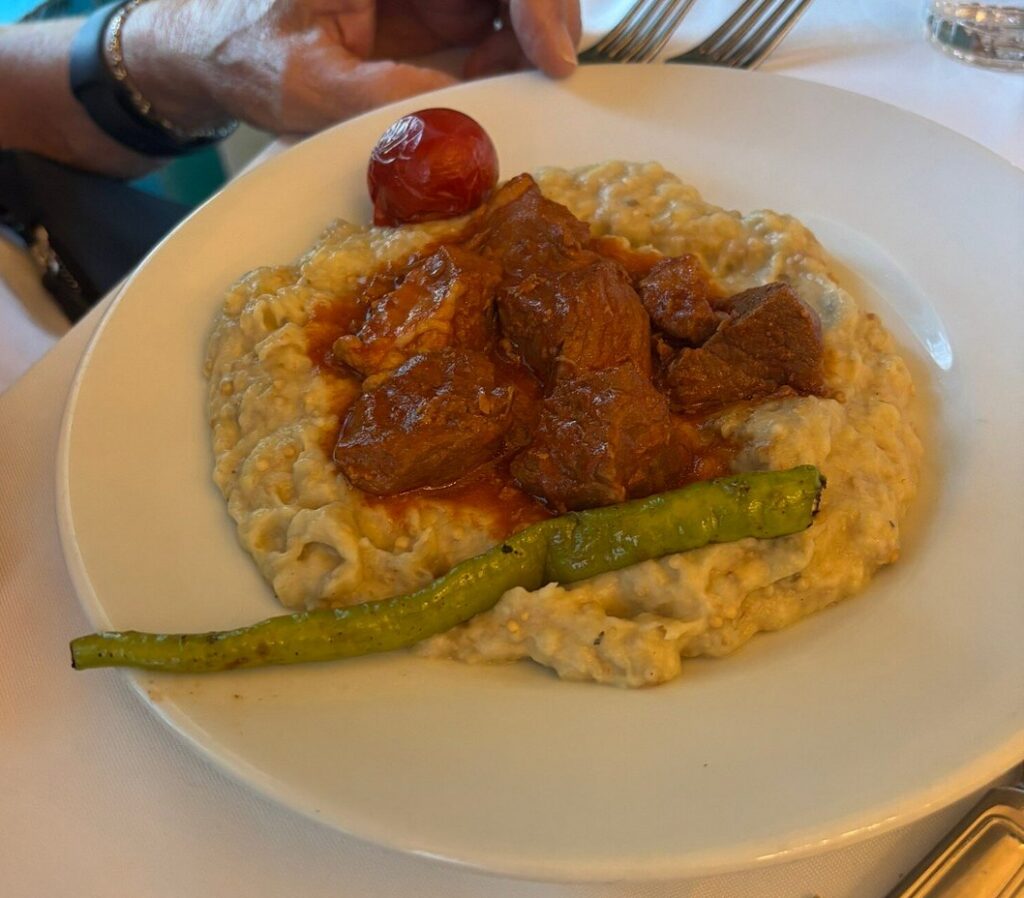 Hünkar beğendi at Pandeli restaurant Istanbul — braised lamb on smoky charred eggplant purée, served with roasted pepper and tomato