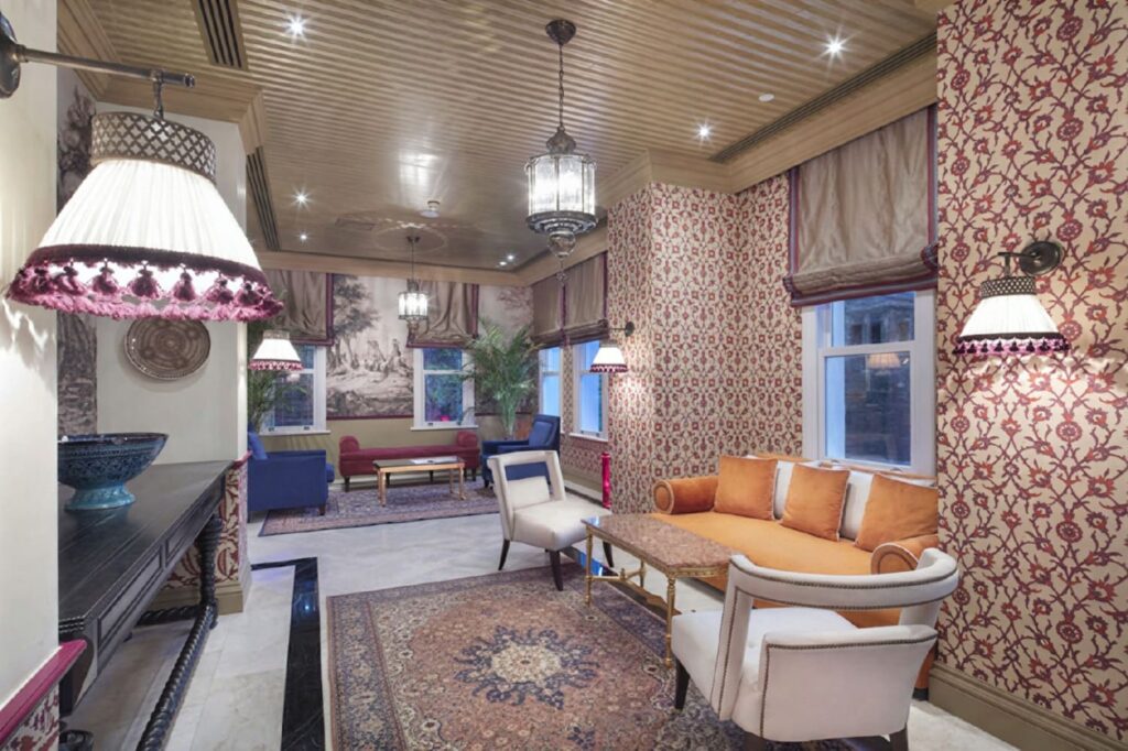 Hagia Sofia Mansions lobby lounge with Ottoman floral wallpaper, handwoven Persian carpet, terracotta sofa and layered lantern lamps, Sultanahmet