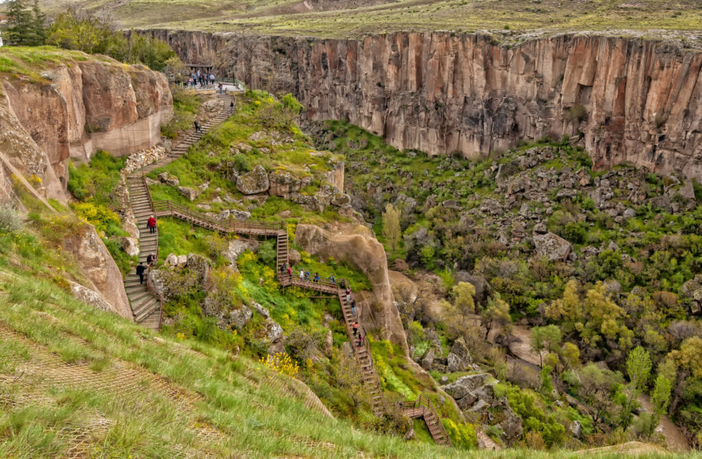 Wooden hiking trail descending into Ihlara Valley in Aksaray, Turkey, surrounded by volcanic rock cliffs.