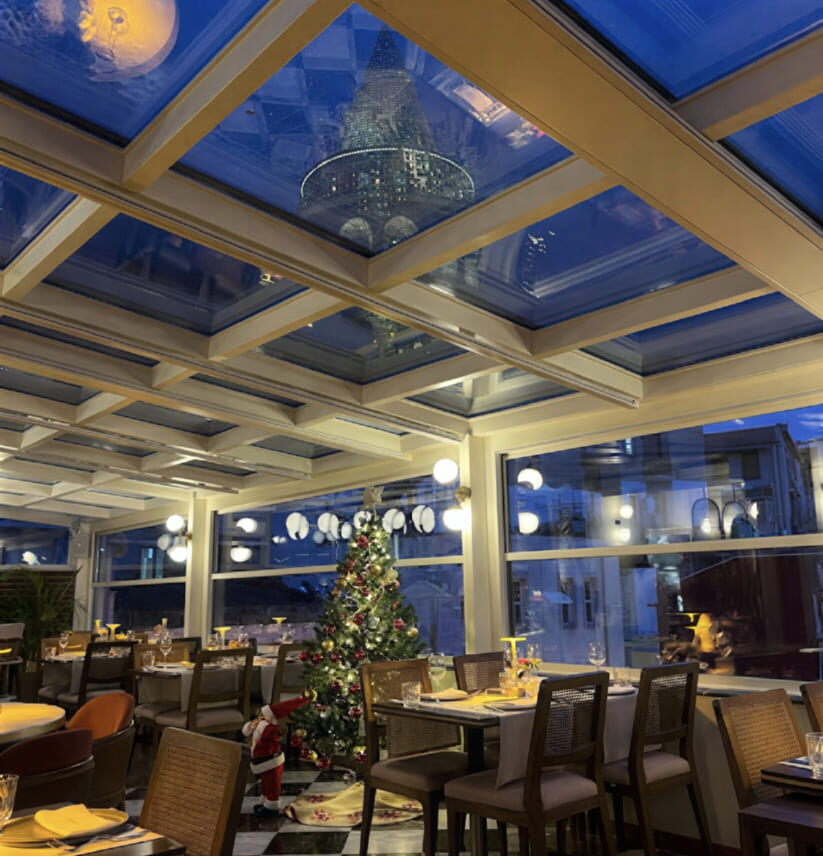 Manifest Roof Restaurant festively decorated for Christmas with a lit tree under the glass skylight ceiling