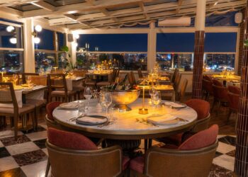 Elegant nighttime table setting at Manifest Roof Restaurant with champagne and illuminated Istanbul mosque skyline