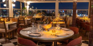 Elegant nighttime table setting at Manifest Roof Restaurant with champagne and illuminated Istanbul mosque skyline