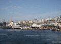 The Rahmi M. Koç Museum waterfront in Hasköy, Istanbul, seen from the Golden Horn: the TCG Uluçalireis submarine and Fenerbahçe ferry moored side by side, with white museum canopies, the shore café, and the residential hillside rising behind