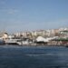 The Rahmi M. Koç Museum waterfront in Hasköy, Istanbul, seen from the Golden Horn: the TCG Uluçalireis submarine and Fenerbahçe ferry moored side by side, with white museum canopies, the shore café, and the residential hillside rising behind
