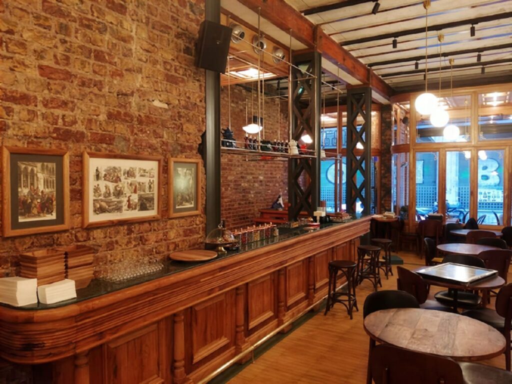 Salon Galata bar counter — exposed red brick wall, dark wood bar and framed historical photographs at Bozkurt Han, Karaköy