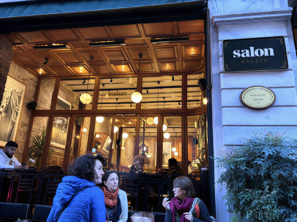 Salon Galata at dusk — glowing wooden facade and sidewalk tables on Bankalar Caddesi, Karaköy