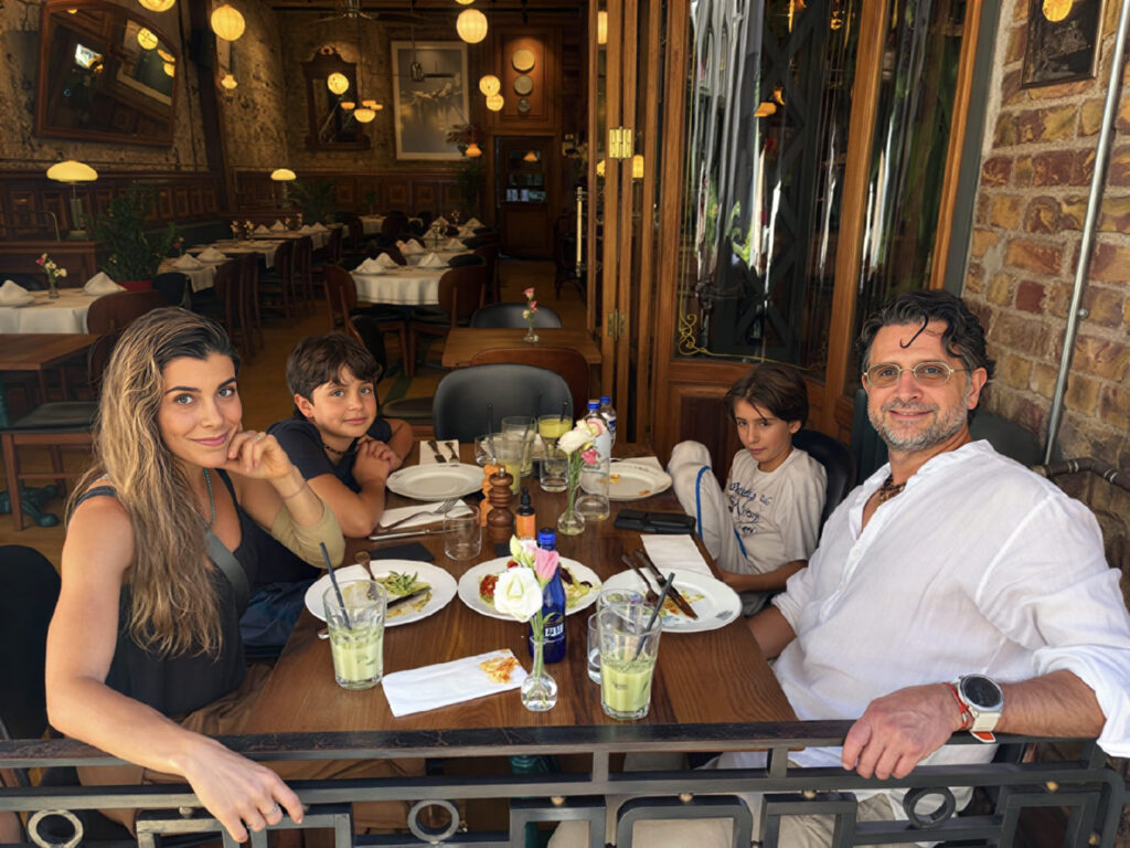 Family dining at Salon Galata's terrace on Bankalar Caddesi — open folding doors and globe-lit interior behind, Karaköy