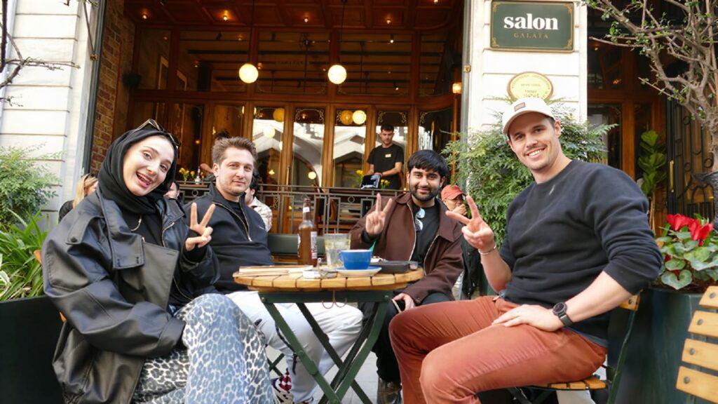 Guests at Salon Galata's outdoor sidewalk tables on Bankalar Caddesi, Karaköy — the restaurant entrance and signage behind