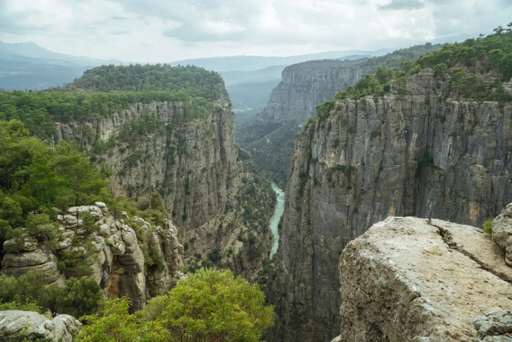Panoramic view of Tazı Canyon in Antalya, with towering limestone cliffs overlooking the Köprüçay River below.