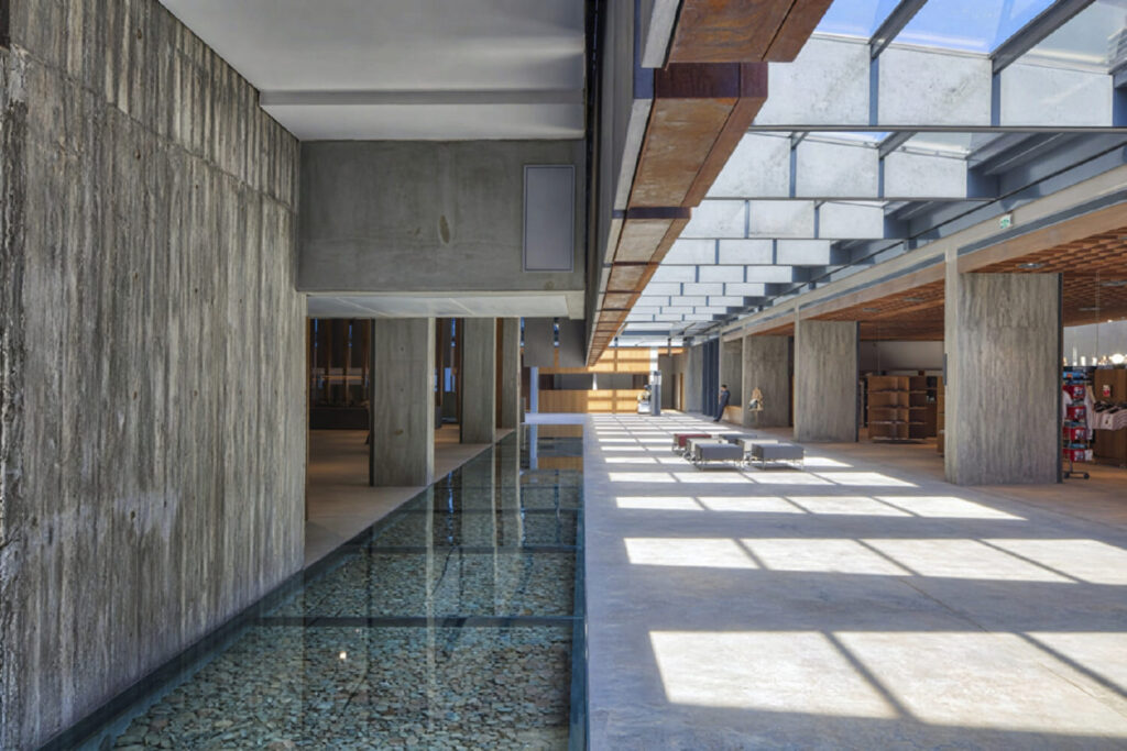 Sunlit interior corridor at the Troy Museum with a glass floor over a shallow reflecting pool