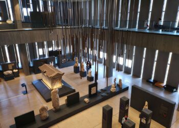 Elevated view of the Troy Museum's main gallery atrium with statues and a marble sarcophagus