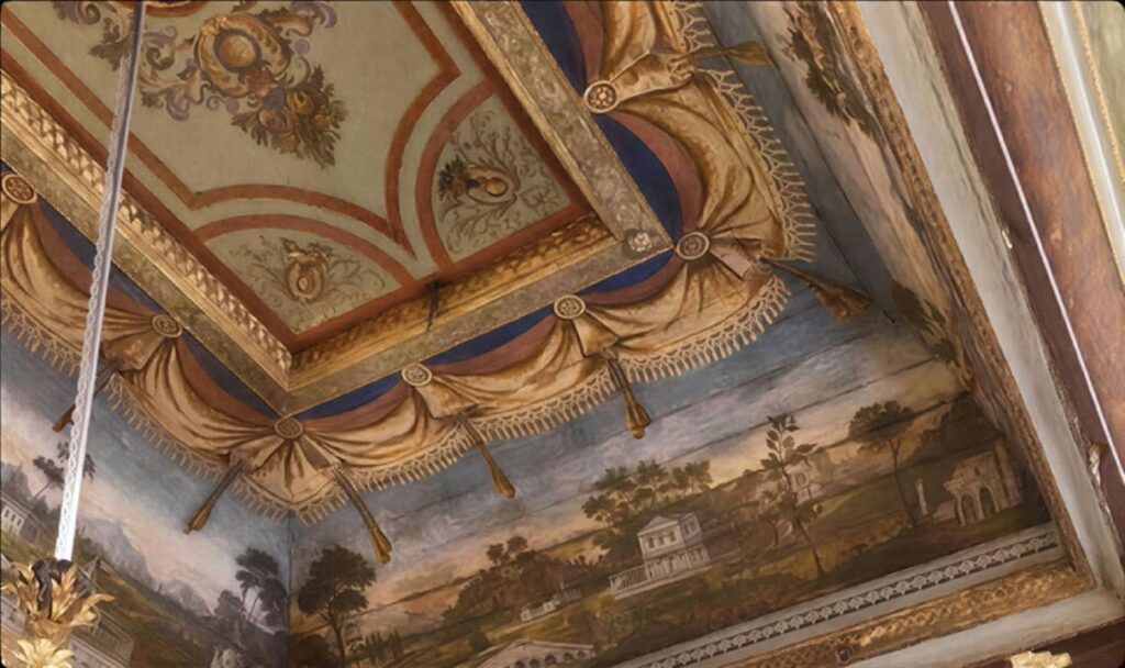 Ornate painted ceiling of Yanbol Synagogue in Istanbul with gilded baroque frames, draped swag motifs, and pastoral landscape murals